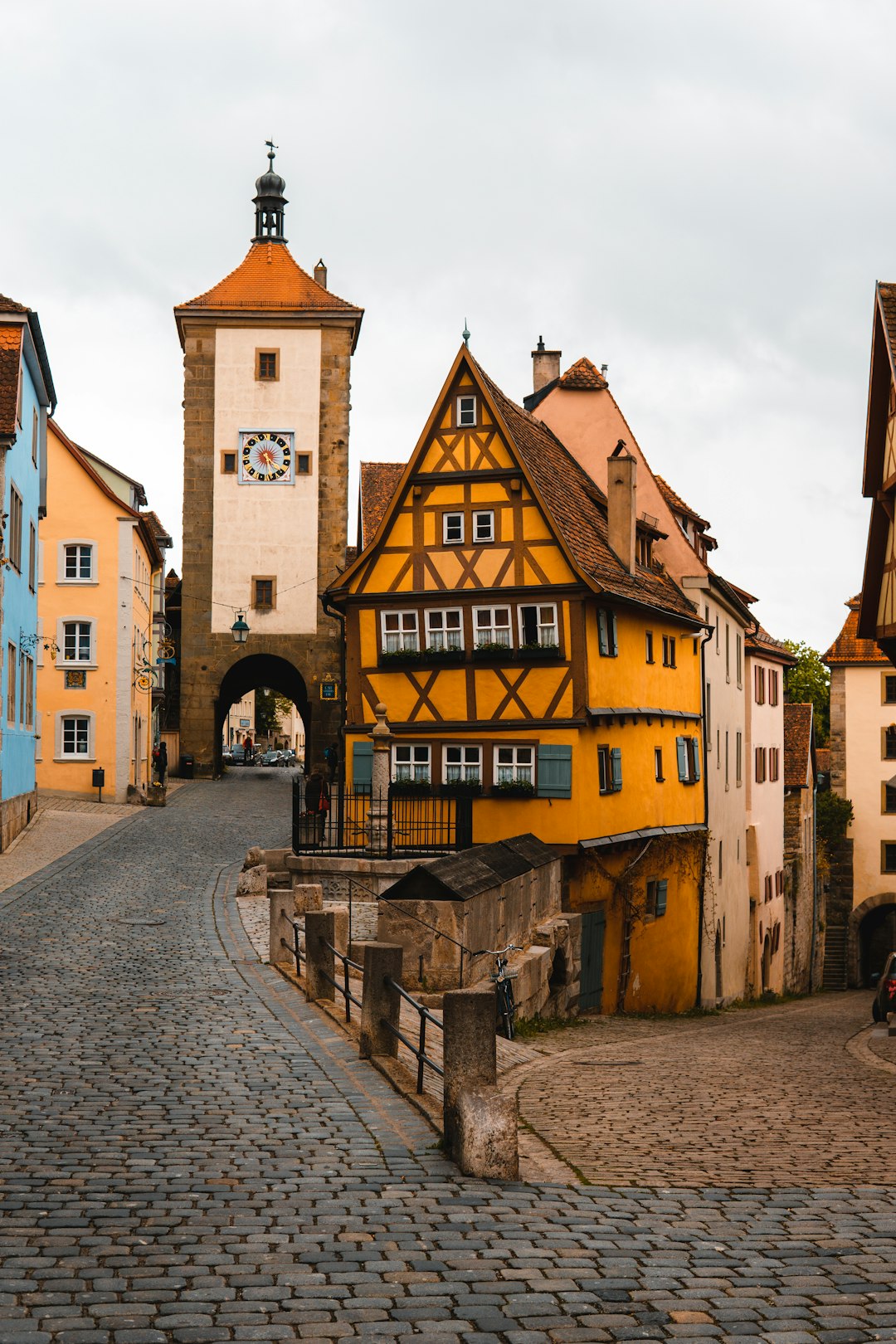 gallery-08 a-cobblestone-road-with-a-yellow-building-and-a-clock-tower-in-the-background-jyccp4kq73m