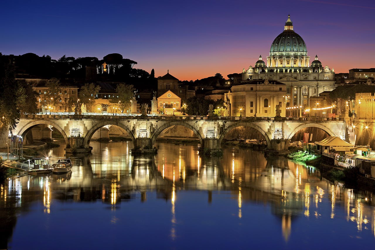 about-me-01 Beautiful view of Saint Peters Basilica and St. Angelo Bridge in Rome at sunset reflecting in the Tiber River.